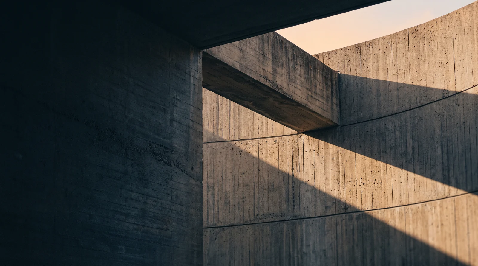 Dramatic concrete architecture framed by deep shadows and warm sunlight